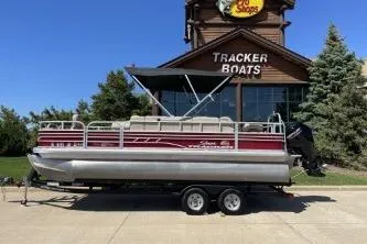 The Image of 2022 Sun Tracker Fishin' Barge 20 DLX pontoon boat on trailer outside Tracker Boats store. - 1