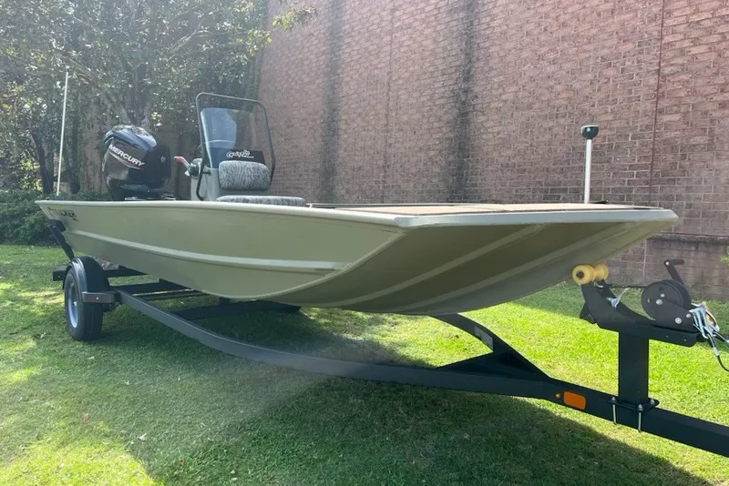 The Image of 2026 Tracker Grizzly 1860 CC boat on trailer, parked on grass near brick wall. - 0