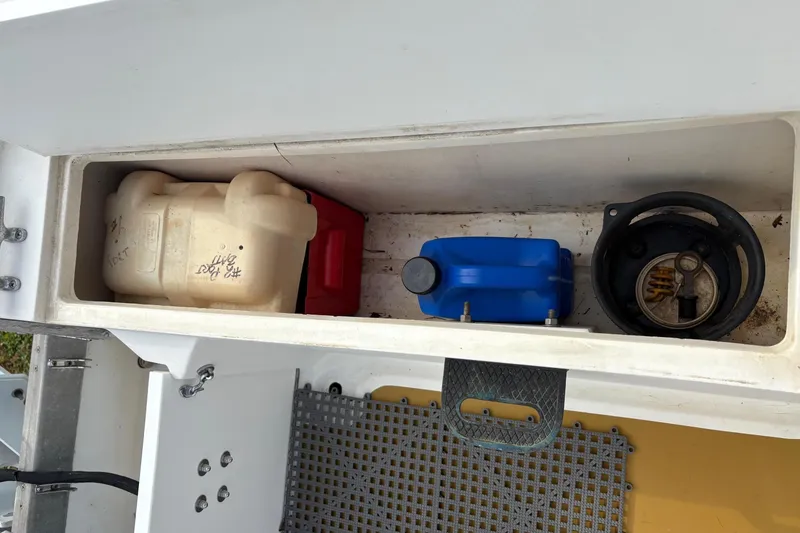 Slide: The Image of Storage compartment of a 1979 Mako Pro Skiff 21 CC boat with various containers. - 10