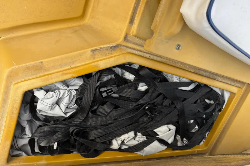 Slide: The Image of Storage compartment of a 1979 Mako Pro Skiff 21 CC with black straps and fabric. - 13