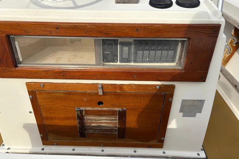 Slide: The Image of 1979 Mako Pro Skiff 21 CC dashboard with wooden paneling and control switches. - 8