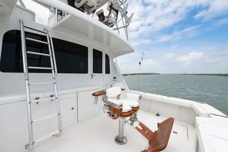 Slide: The Image of 2005 Cabo 40 Flybridge yacht deck with fishing chair and ladder, overlooking calm waters. - 13