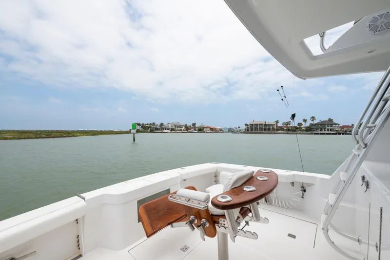 Slide: The Image of 2005 Cabo 40 Flybridge yacht with fishing chair, overlooking coastal homes and calm waters. - 17