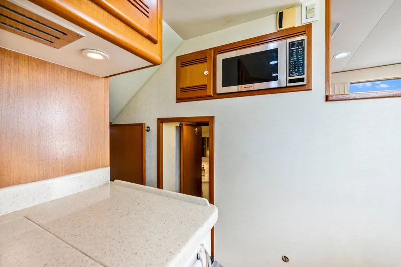 Slide: The Image of Interior of 2005 Cabo 40 Flybridge yacht with microwave and wooden cabinetry. - 24
