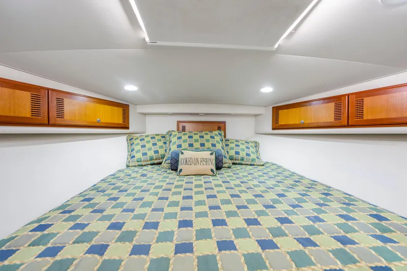Slide: The Image of Cozy cabin interior of 2005 Cabo 40 Flybridge with checkered bedding and wooden cabinets. - 25