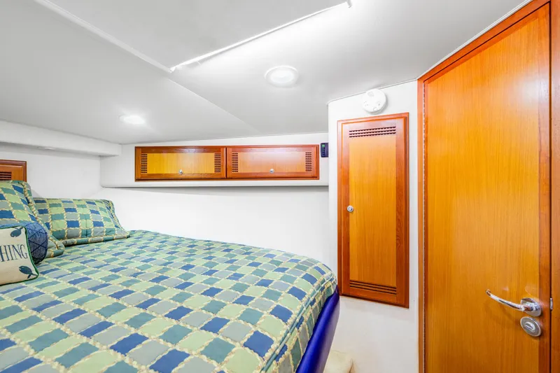 Slide: The Image of Cozy cabin interior of 2005 Cabo 40 Flybridge with checkered bedding and wooden cabinets. - 27