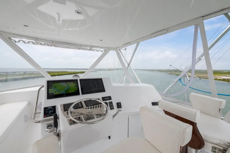 Slide: The Image of Flybridge of 2005 Cabo 40 yacht with steering wheel and navigation screens, overlooking waterway. - 4
