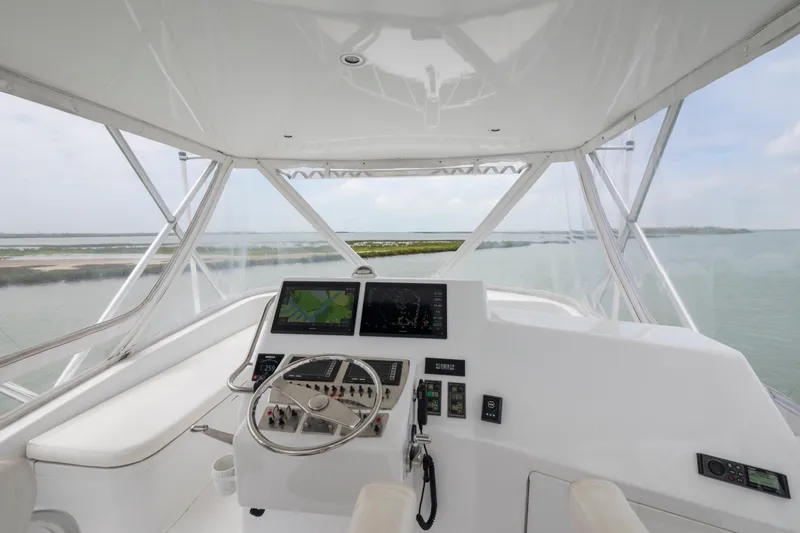 Slide: The Image of Flybridge helm of 2005 Cabo 40, featuring navigation screens and steering wheel, overlooking water. - 5