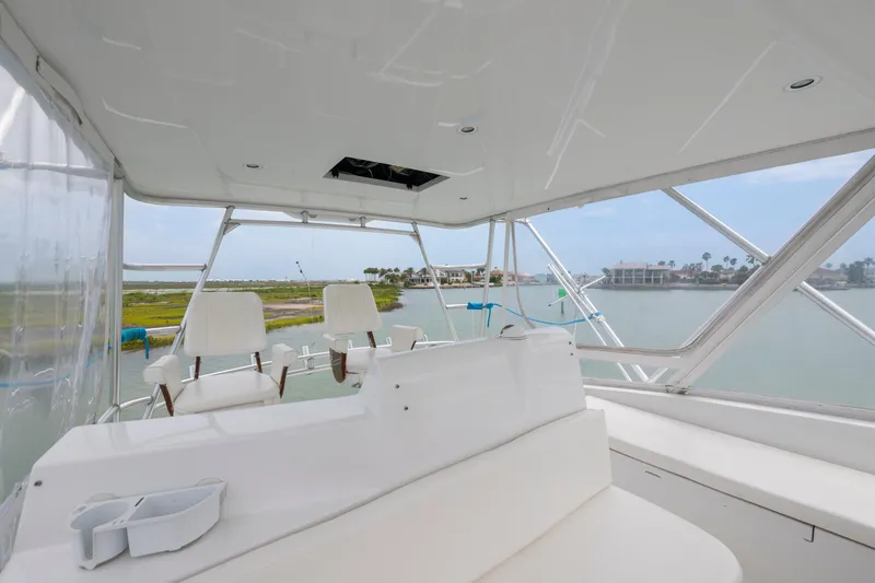 Slide: The Image of Flybridge view of 2005 Cabo 40 yacht overlooking serene waterfront and distant buildings. - 9