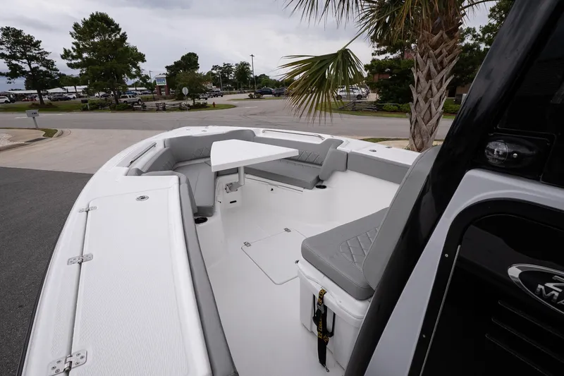 Slide: The Image of 2026 Blazer Bay Makaira 2600 boat interior with seating and table, parked near palm trees. - 16