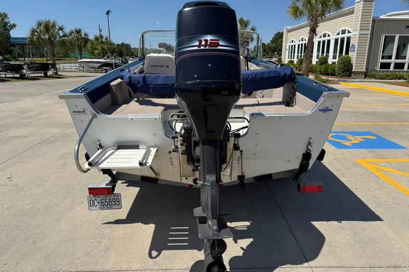 Slide: The Image of 1997 Starcraft Stardeck 190 Fish boat with outboard motor in a parking lot. - 4