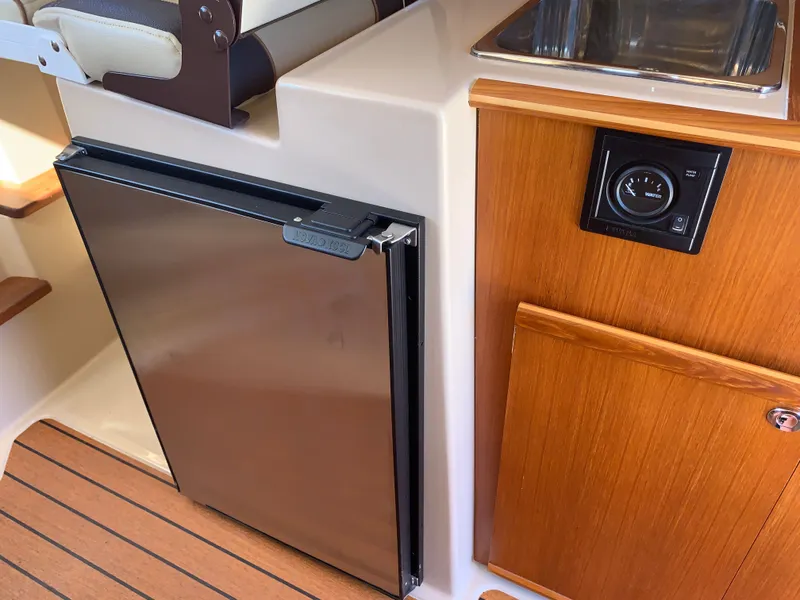 Slide: The Image of Interior of 2018 Ranger Tugs R-23 with fridge and wood paneling. - 15