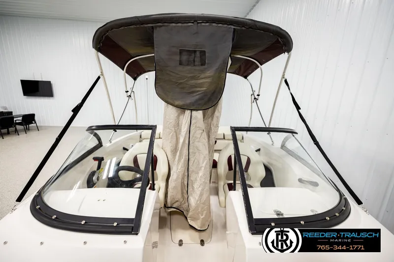 Slide: The Image of 2016 Tahoe 450 TS boat with canopy in showroom, featuring dual seating and steering wheel. - 25