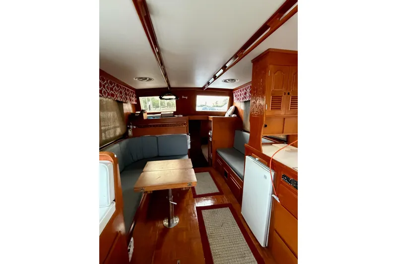 Slide: The Image of 1988 Marine Trader 34 Double Cabin interior with wood finish, seating, and compact kitchen area. - 10
