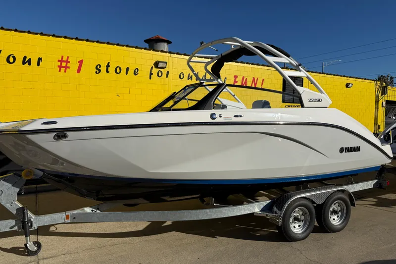Slide: The Image of 2026 Yamaha Boats 222SD on trailer, parked by a yellow building. - 2