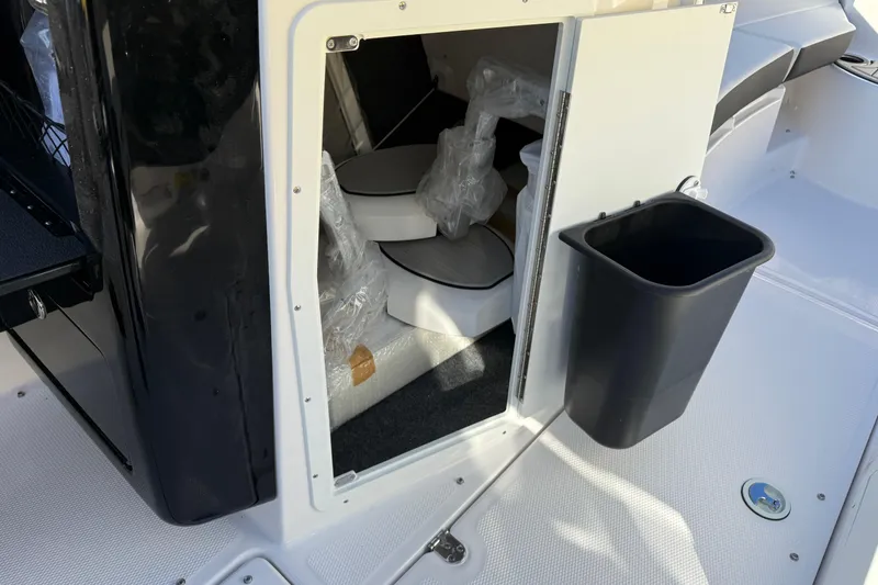 Slide: The Image of 2026 Yamaha Boats 222SD storage compartment with black trash bin on deck. - 22