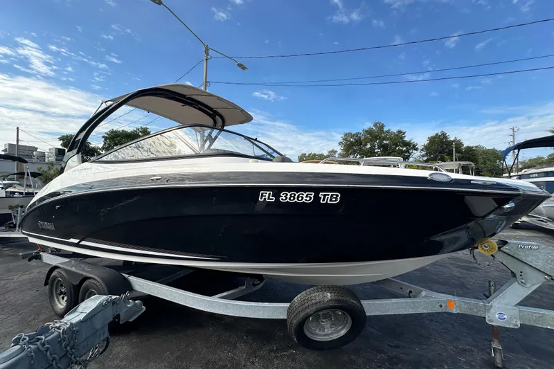 Slide: The Image of 2017 Yamaha Boats 242 Limited S on trailer, sleek black design under blue sky. - 7