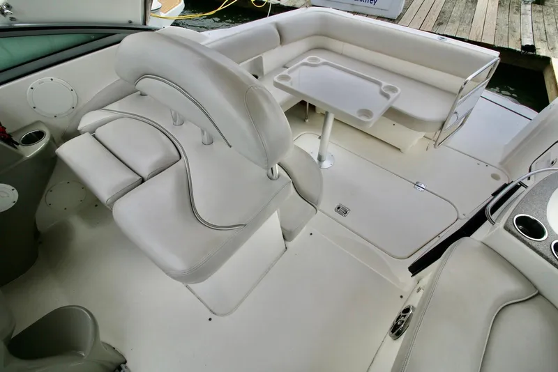 Slide: The Image of 2009 Larson Cabrio 310 boat interior with white seating and table, docked by wooden pier. - 15