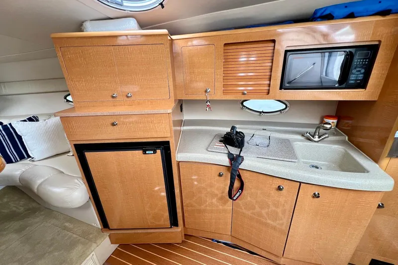 Slide: The Image of 2009 Larson Cabrio 310 cabin kitchen with wood cabinets, sink, and microwave. - 30