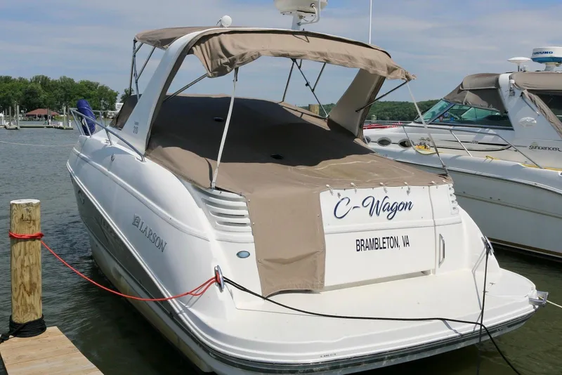Slide: The Image of 2009 Larson Cabrio 310 boat docked, featuring tan canopy and "C-Wagon" name. - 4