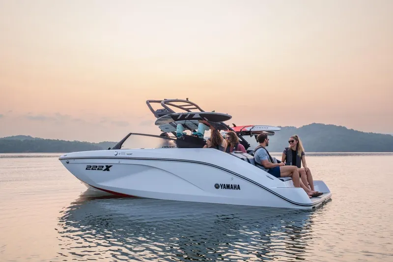 Slide: The Image of 2026 Yamaha Boats 222XD on serene water at sunset with passengers. - 14