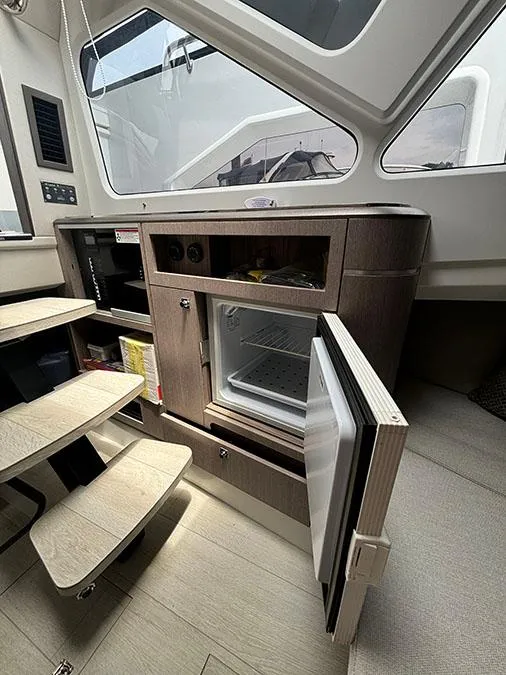 Slide: The Image of Interior of 2024 Galeon 325 GTO yacht with open mini fridge and storage cabinets. - 20