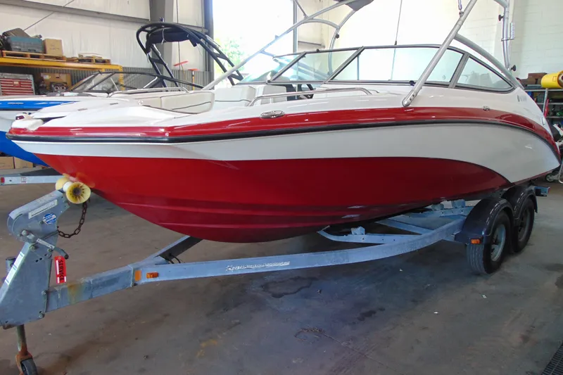 Slide: The Image of 2014 Yamaha AR210 boat with red and white hull on a trailer in a garage. - 3