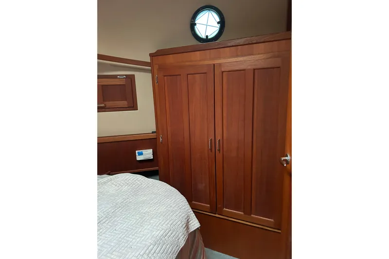 Slide: The Image of Interior of 2003 American Tug 34, featuring wooden cabinetry and a cozy sleeping area. - 13