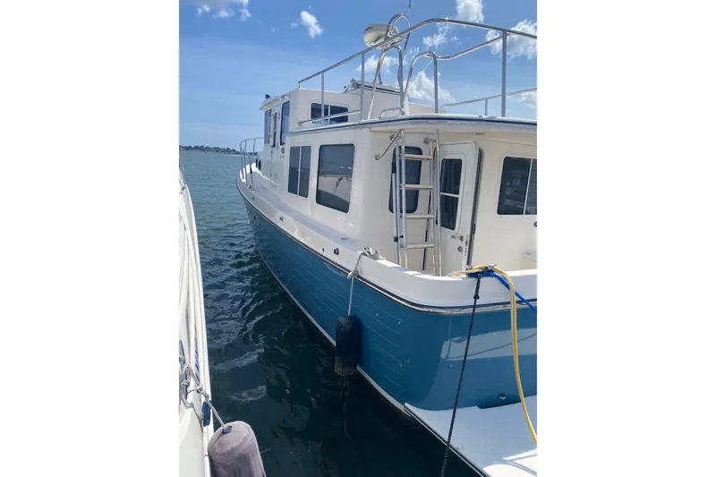 Slide: The Image of 2003 American Tug 34 boat docked on calm water under a clear blue sky. - 2