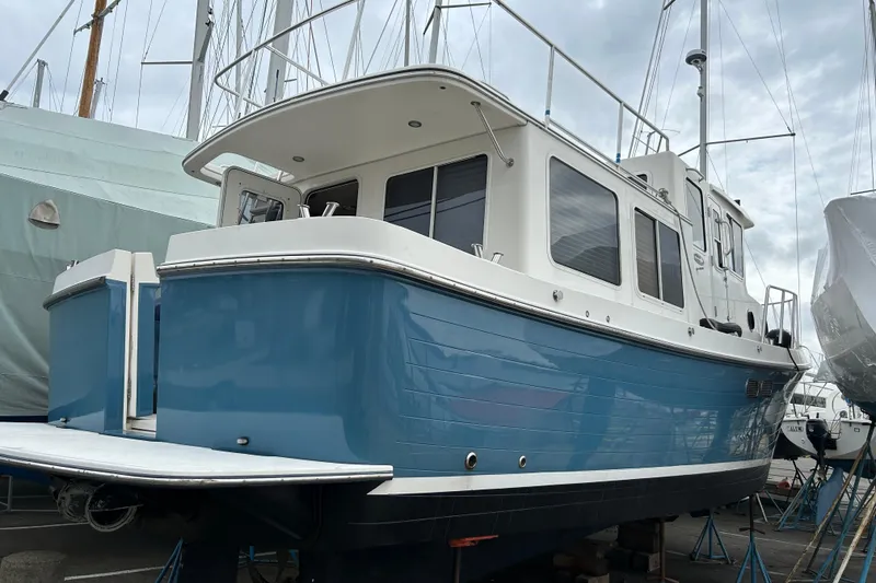 Slide: The Image of 2003 American Tug 34 boat with blue hull, docked in a marina. - 4