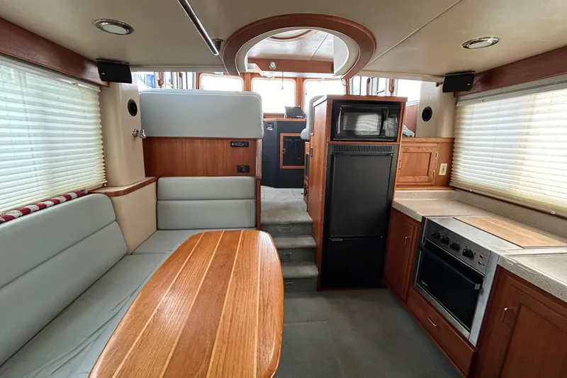 Slide: The Image of Interior of a 2003 American Tug 34, featuring a cozy dining and kitchen area. - 6