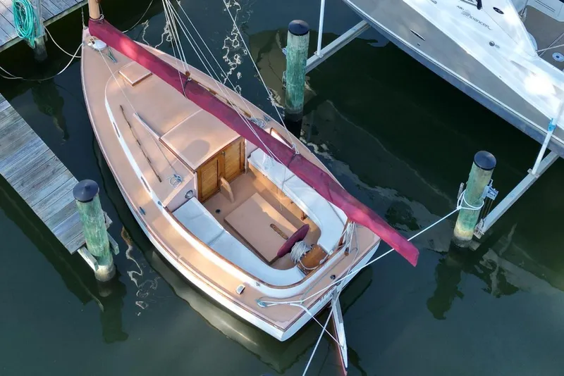 Slide: The Image of 1974 Marshall 22 Cape Cod Catboat docked, featuring a classic design and maroon sail. - 10