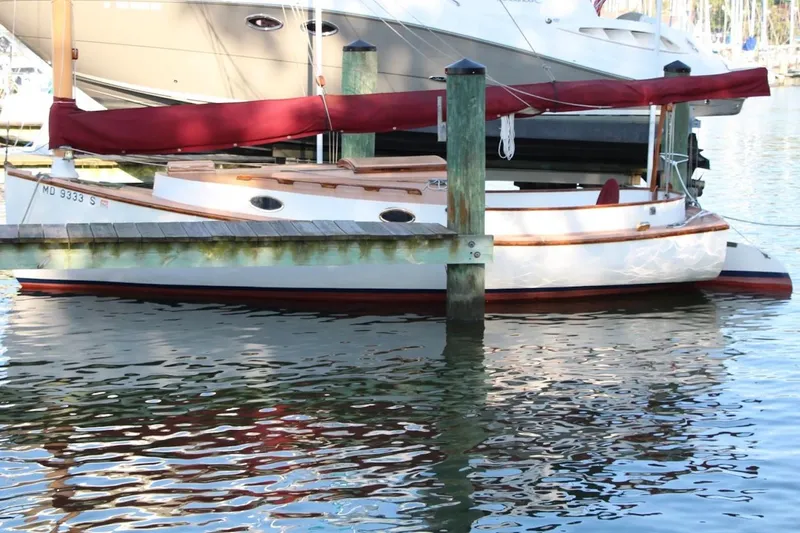 Slide: The Image of 1974 Marshall 22 Cape Cod Catboat docked with red sail cover, reflecting on water. - 4