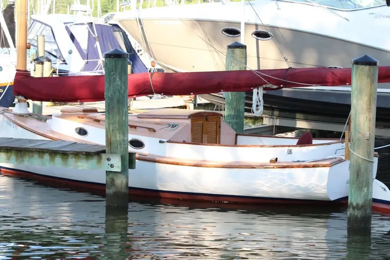 Slide: The Image of 1974 Marshall 22 Cape Cod Catboat docked at marina with red sail cover. - 5