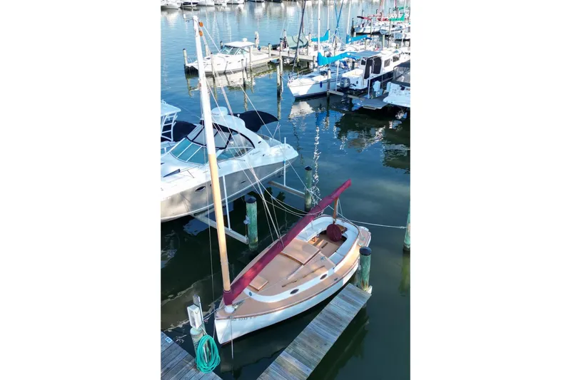 Slide: The Image of 1974 Marshall 22 Cape Cod Catboat docked in a marina, surrounded by other boats. - 7