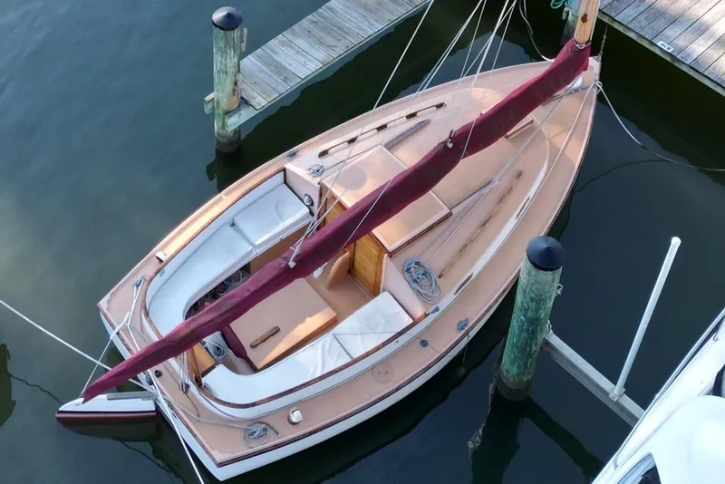 Slide: The Image of 1974 Marshall 22 Cape Cod Catboat docked, featuring classic design and maroon sail cover. - 9