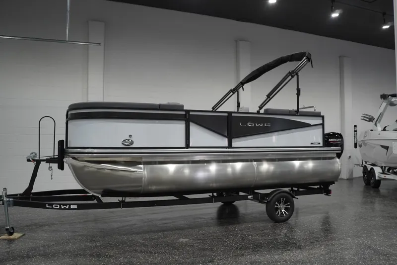Slide: The Image of 2026 Lowe LS 190 pontoon boat on trailer in showroom setting. - 10
