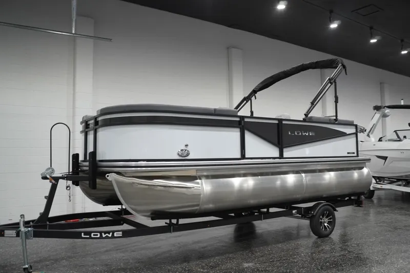Slide: The Image of 2026 Lowe LS 190 pontoon boat on trailer in showroom setting. - 5