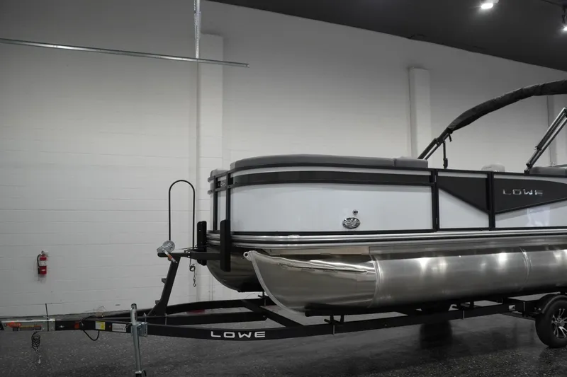 Slide: The Image of 2026 Lowe LS 190 pontoon boat on trailer in indoor showroom. - 6