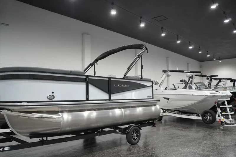 Slide: The Image of 2026 Lowe LS 190 pontoon boat displayed in a showroom with modern lighting. - 7