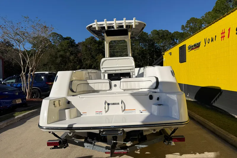 Slide: The Image of 2026 Yamaha Boats 252 FSH Sport, rear view, parked outdoors near a yellow building. - 12