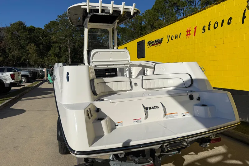 Slide: The Image of 2026 Yamaha Boats 252 FSH Sport, rear view, parked outdoors near a yellow building. - 13