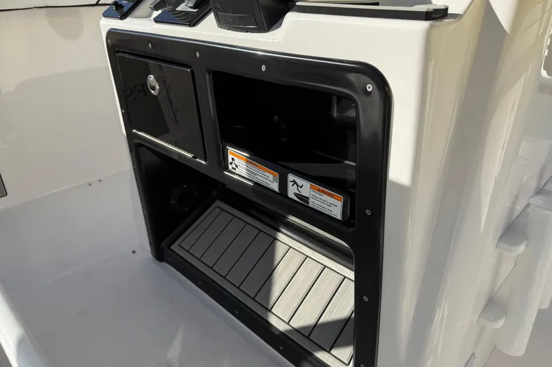 Slide: The Image of 2026 Yamaha Boats 252 FSH Sport console storage area with safety labels. - 19