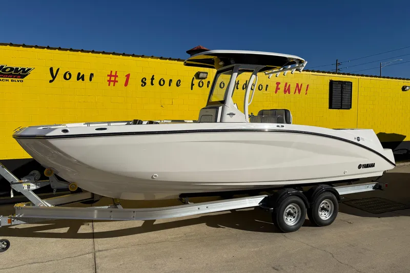 Slide: The Image of 2026 Yamaha Boats 252 FSH Sport on trailer, parked near yellow building. - 3