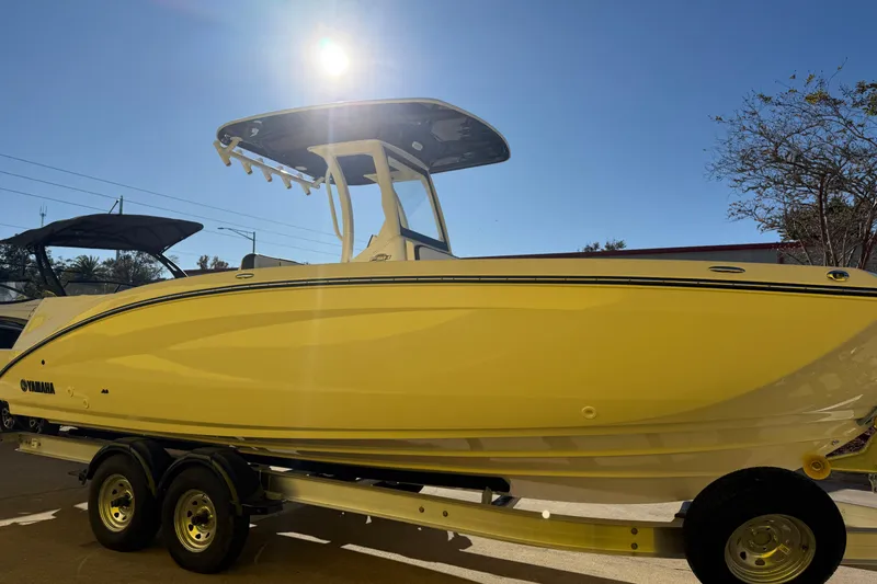 Slide: The Image of 2026 Yamaha Boats 252 FSH Sport in yellow, displayed on a trailer under a clear sky. - 9