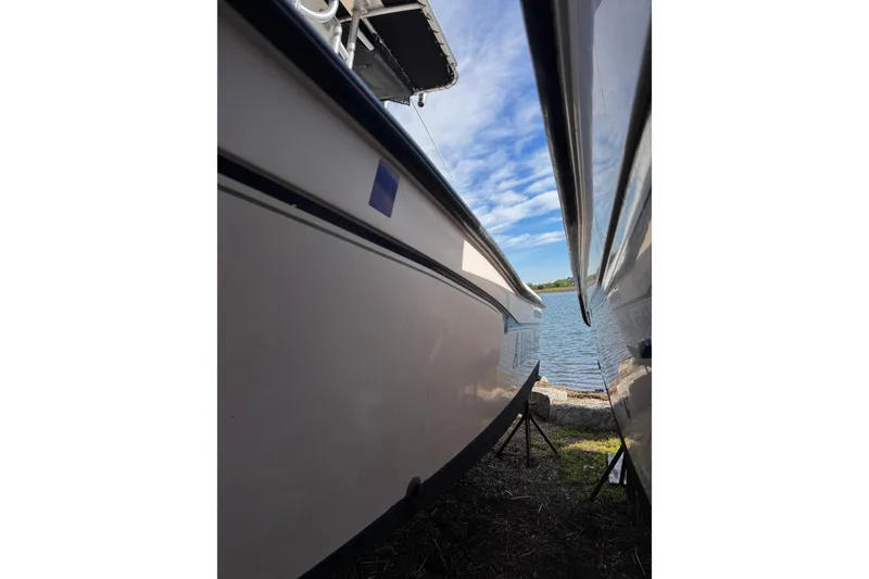 Slide: The Image of 1999 Grady-White Fisherman 222 boat docked near a serene lake under a blue sky. - 12