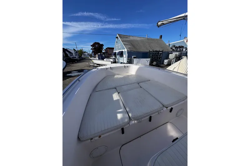 Slide: The Image of 1999 Grady-White Fisherman 222 boat interior with cushioned seating, docked under clear blue sky. - 7