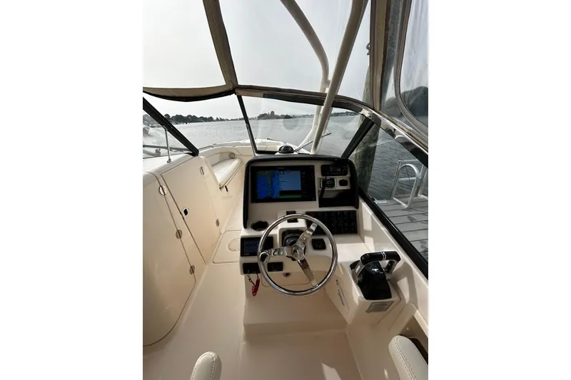 Slide: The Image of 2016 Grady-White Freedom 275 boat cockpit with steering wheel and navigation system. - 2