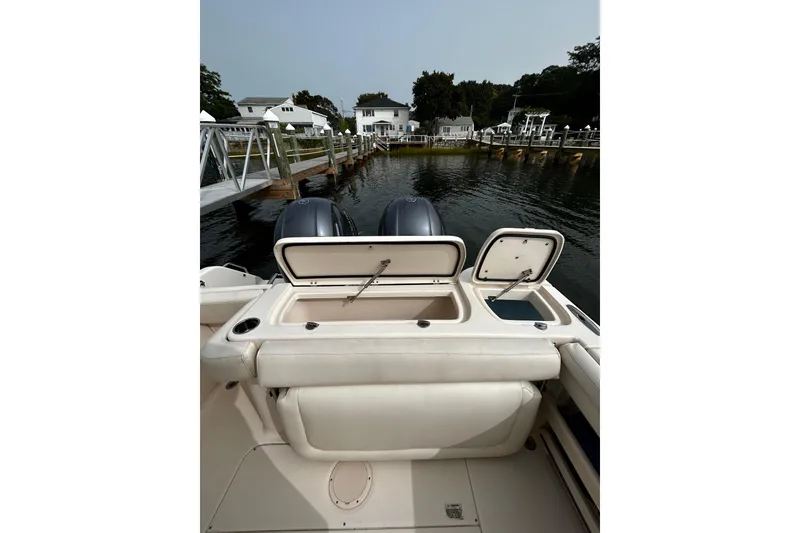 Slide: The Image of 2016 Grady-White Freedom 275 boat with open storage compartments, docked by waterfront homes. - 3
