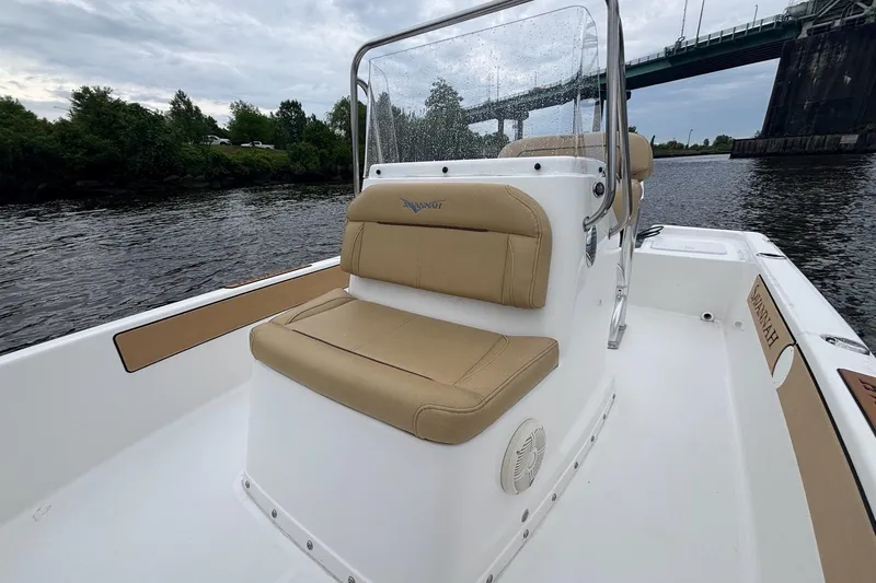 Slide: The Image of 2025 Savannah 190 IS boat interior with tan seating, on a river under a bridge. - 10